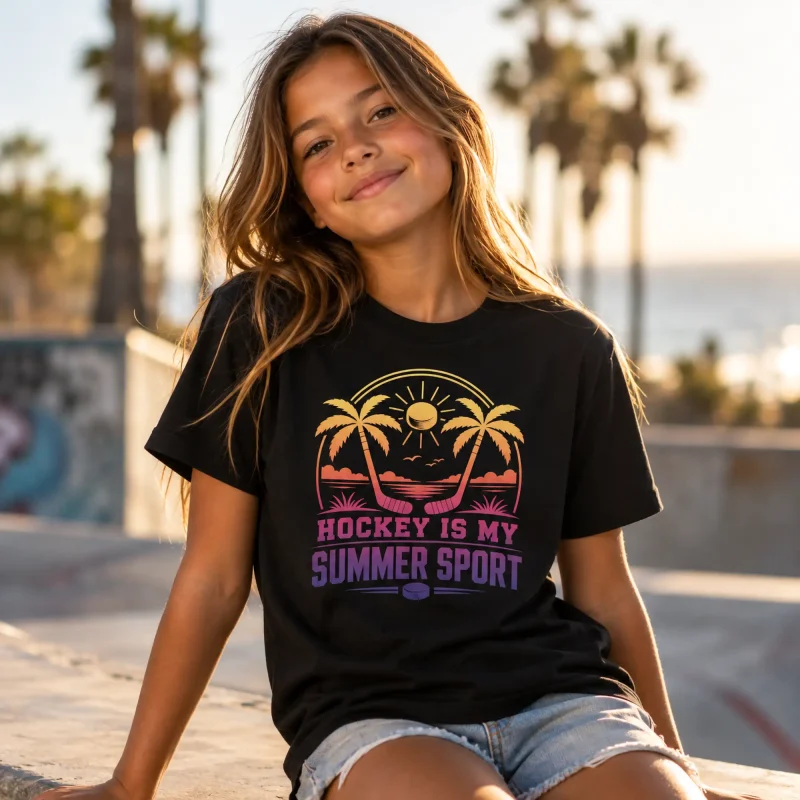 Girl wearing a black Hockey Is My Summer Sport youth t-shirt with a sunset, palm trees and crossed hockey sticks design